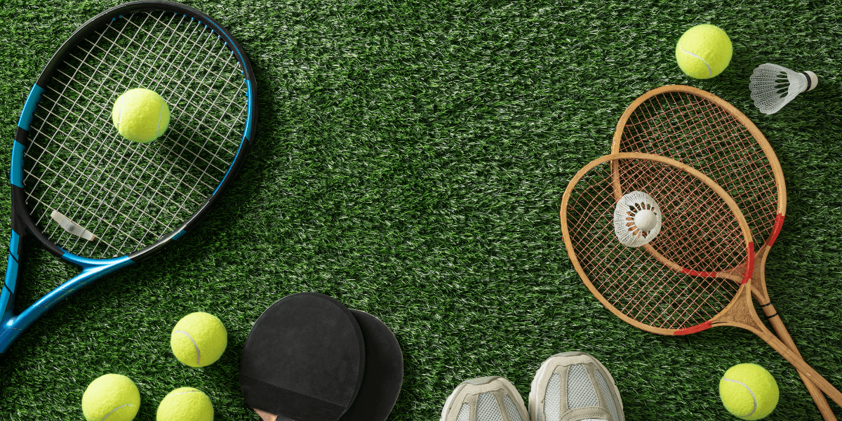 Tennis rackets, tennis balls, badminton rackets, and a shuttlecock on artificial grass
