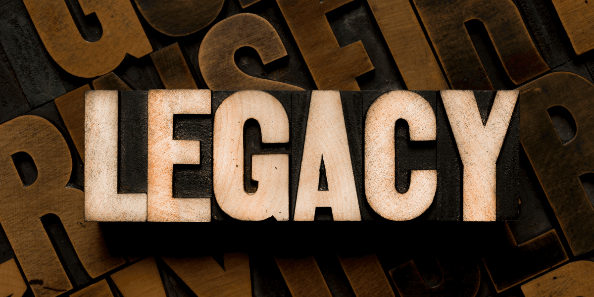 Wooden block letters spelling "LEGACY" on a textured background of assorted letterpress type.