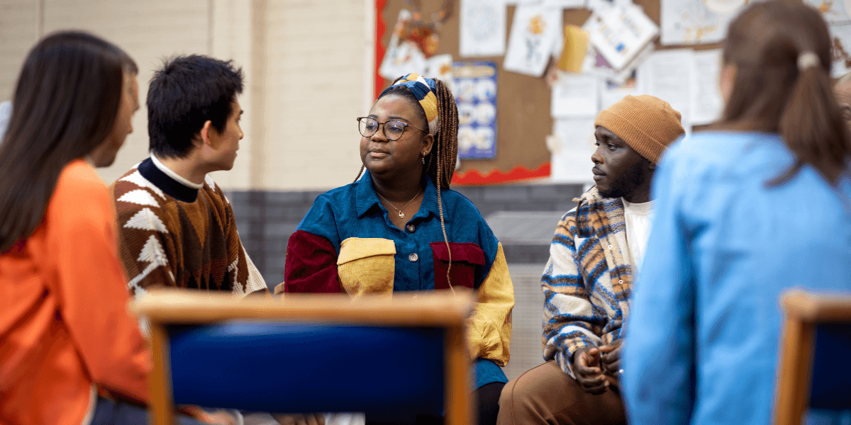 A diverse group of young people sitting in a circle engaged in conversation