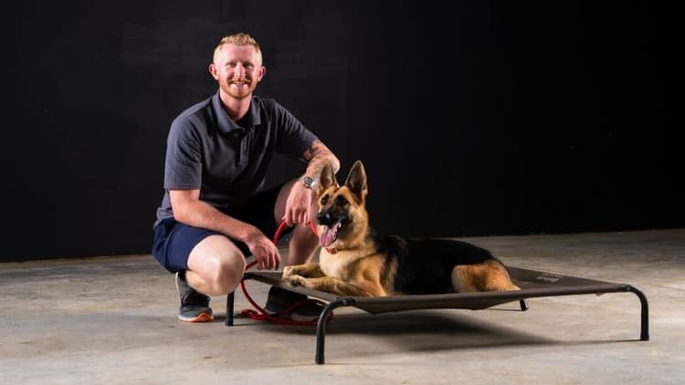 Chandler Hunt posing with a German Shepherd on an elevated training platform.