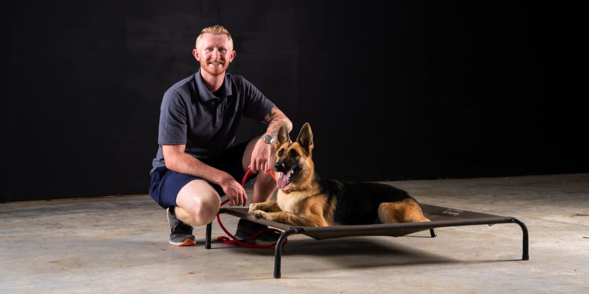 Chandler Hunt posing with a German Shepherd on an elevated training platform.