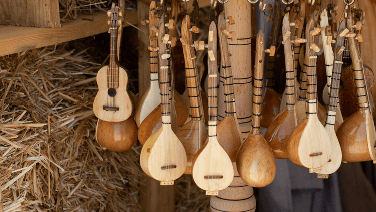 A collection of wooden string instruments hanging against a rustic background.