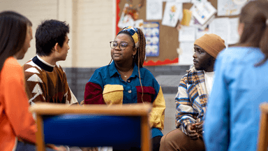 A diverse group of young people sitting in a circle engaged in conversation
