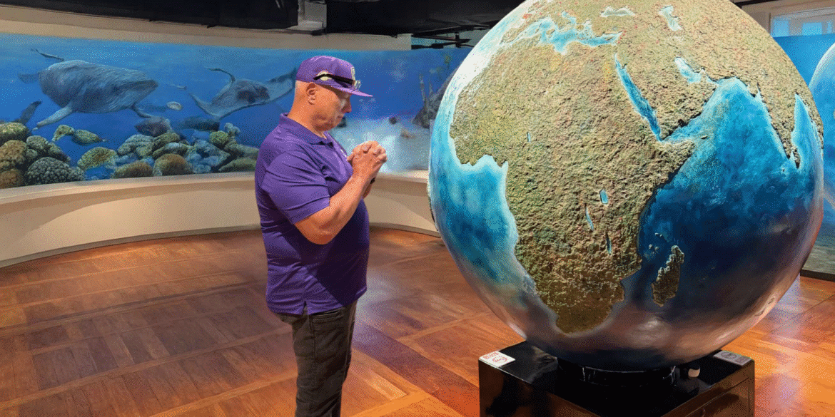 Apostle Constantine I. Nightingdale reflects on the Earth, contemplating spiritual insights in an art gallery setting.